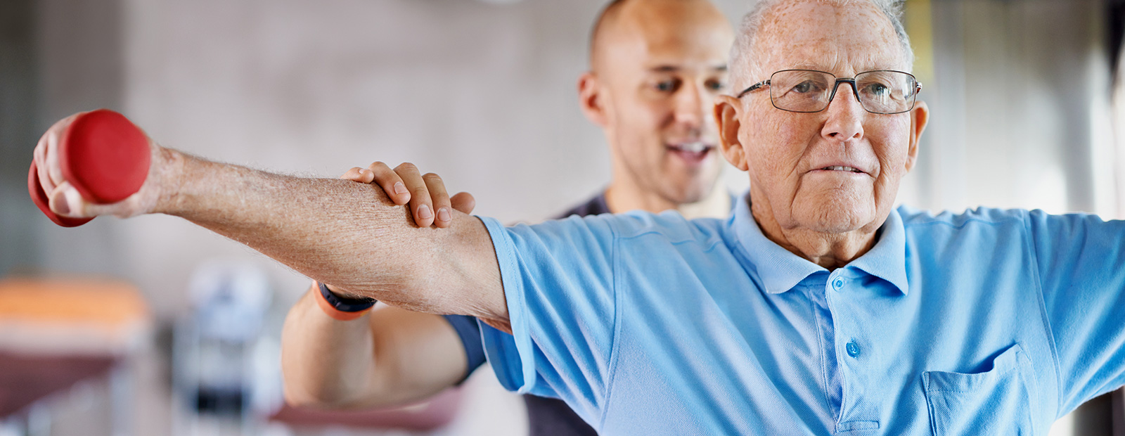 younger man helping elderly man with weights