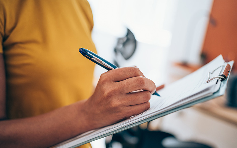 close up of a woman writing on a clipboard