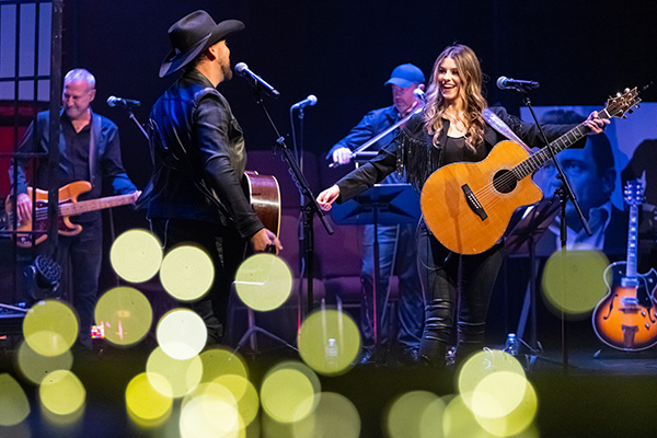 male and female country music artists on stage singing and playing guitar