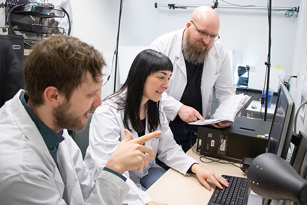 three researchers looking at a laptop