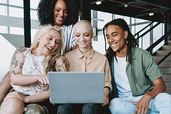 group of diverse individuals looking at a laptop