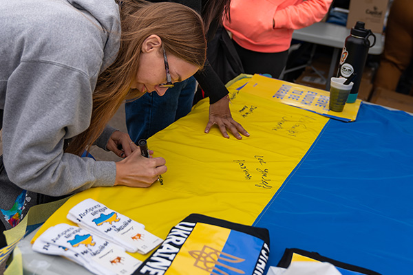 female student writing on a Ukrainian flag