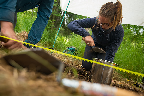 student on the ground with a shovel digging