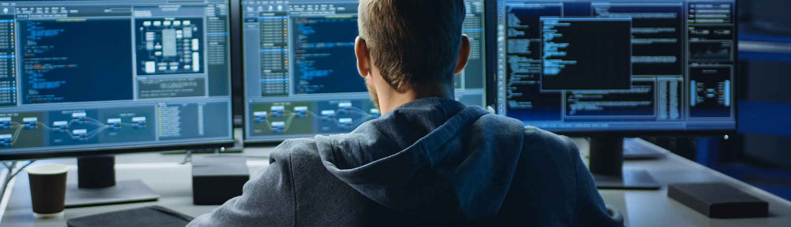 man working on computer with screens showing coding language interfaces