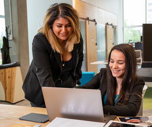 two females talking around laptop