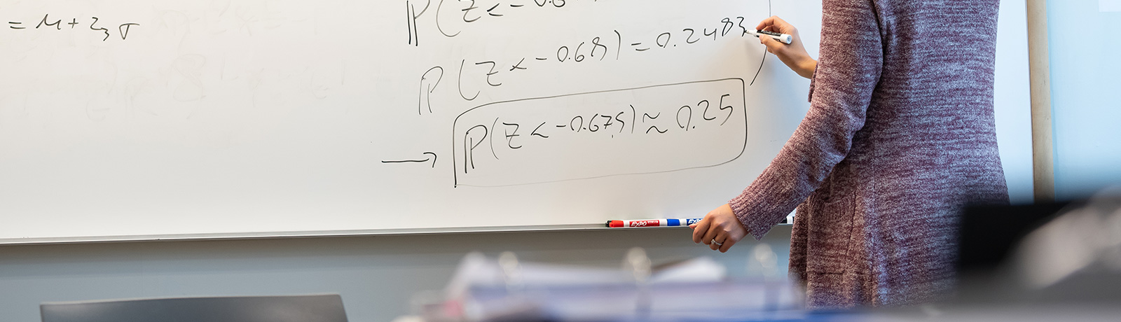 student at whiteboard writing equations