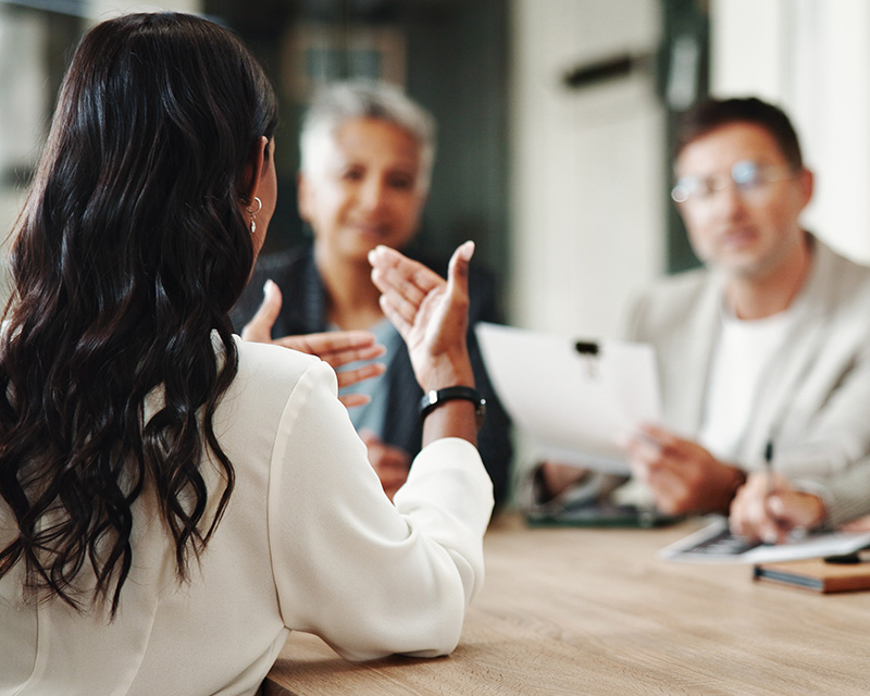 group of people speaking in an office over a table