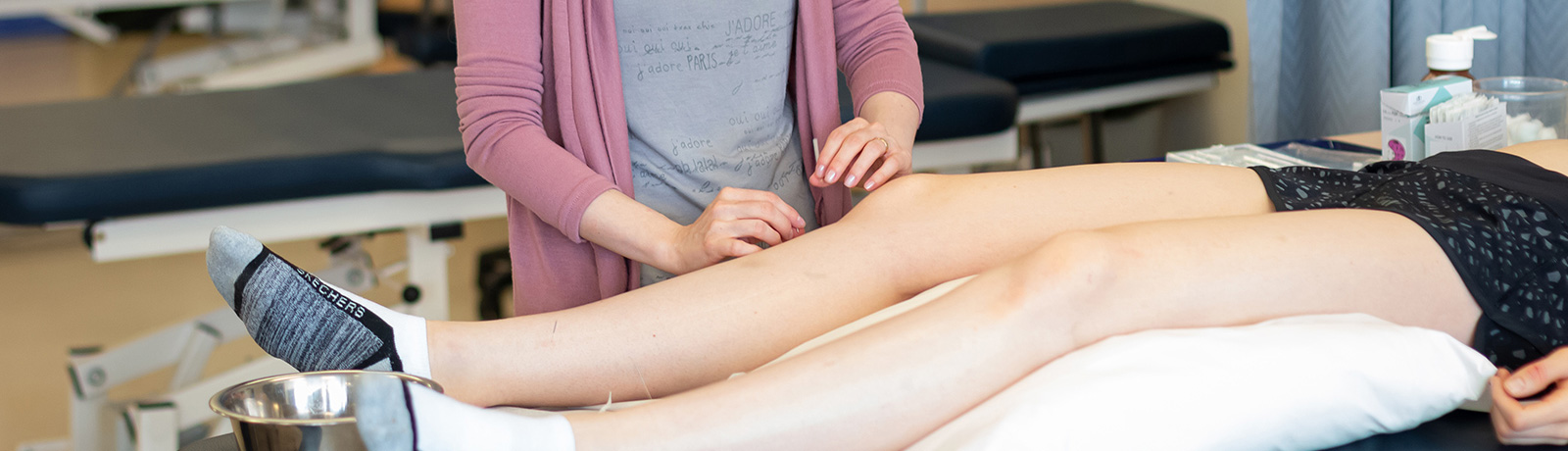 student doing acupuncture on leg