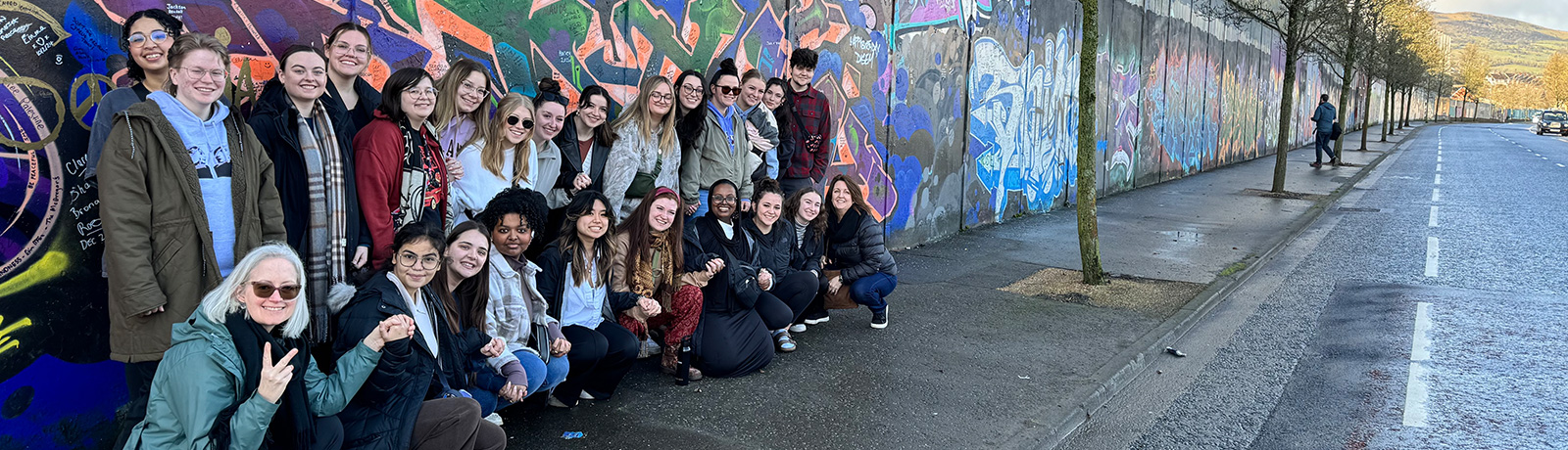 study group in front of a section of the Peace Wall in Belfast