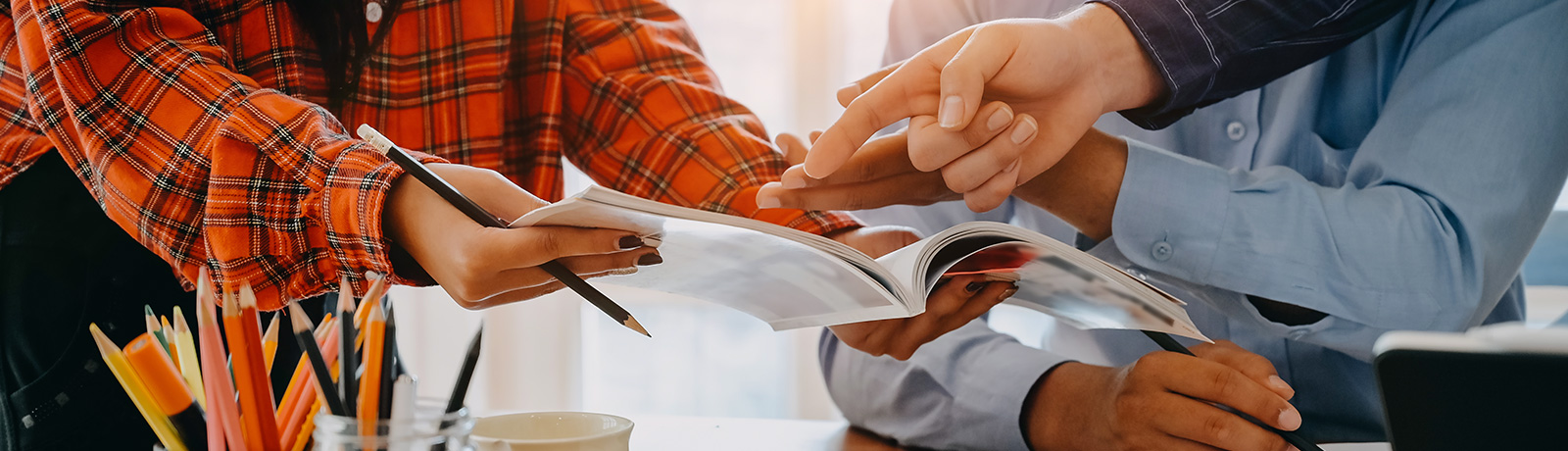 people with pencils reviewing magazine