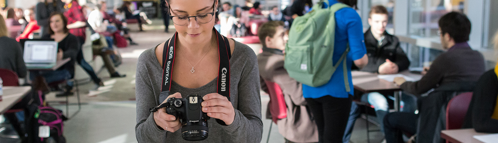 student with camera walking down hallway