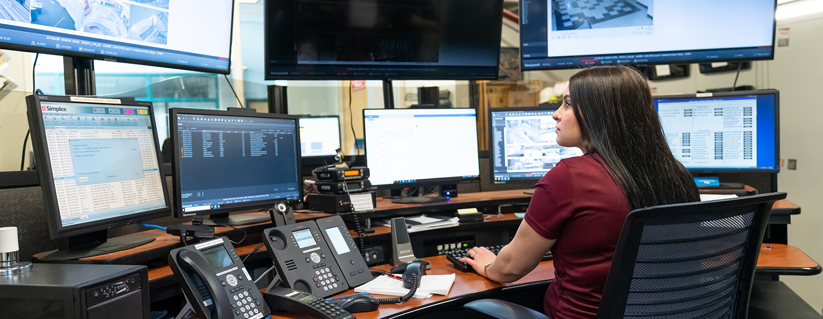 female sitting in front of security monitors