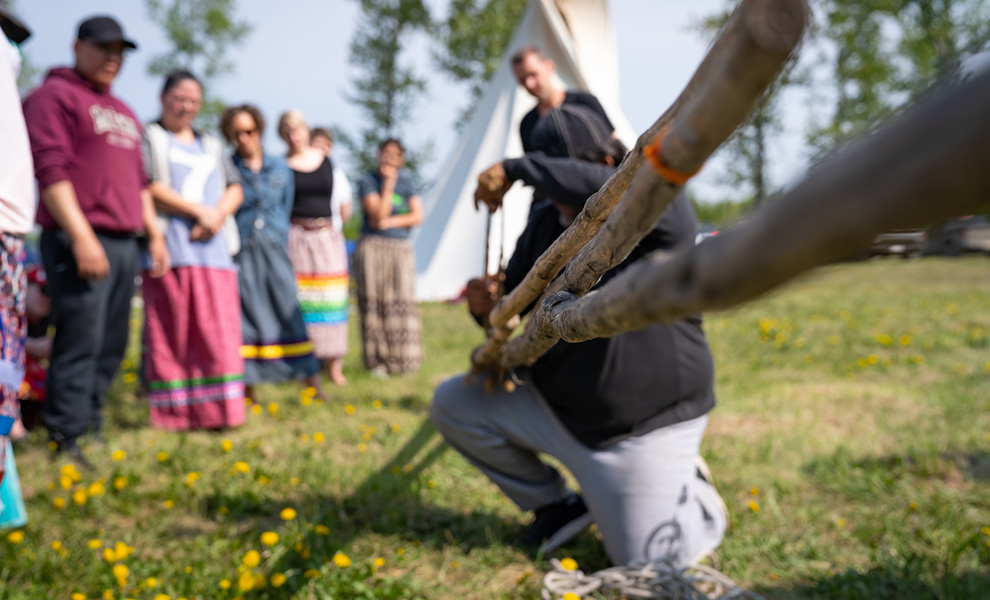 man building a tipi at cultural camp