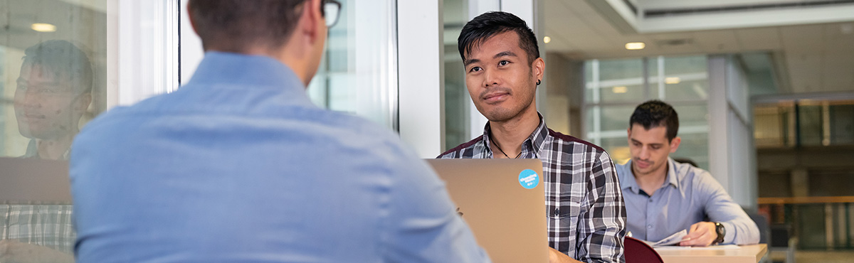 two male students talking over laptop