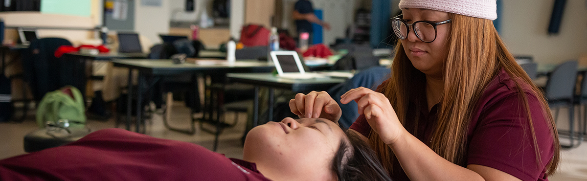 female student massaging another student's face