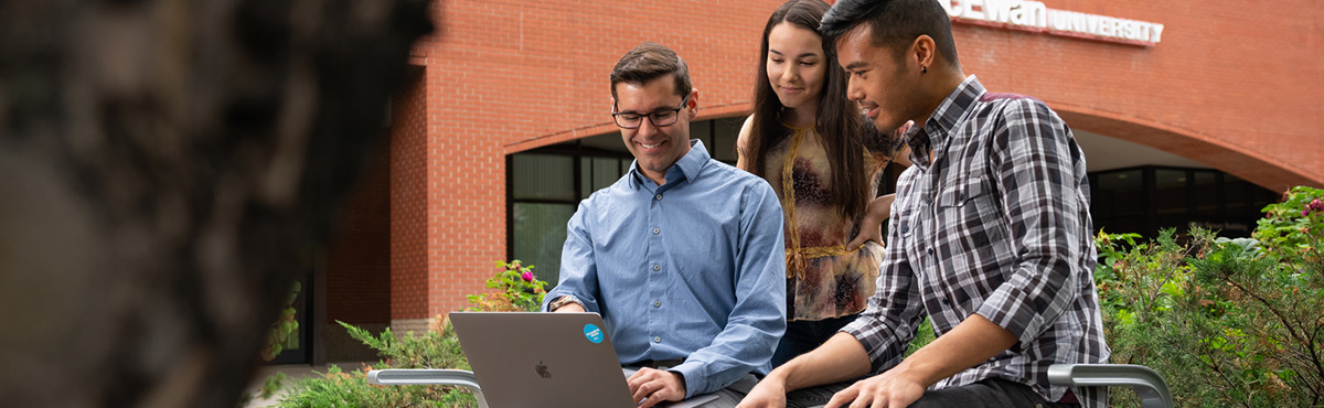 students outside looking at computer