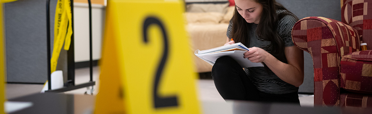 female student taking notes at a crime scene