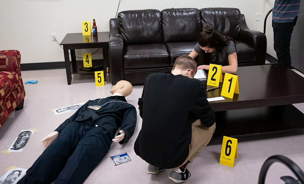 A student takes notes in MacEwan University's crime lab