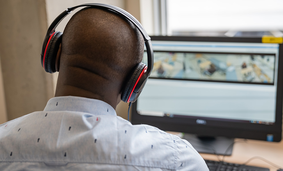 man with headphones on watching simulation on computer