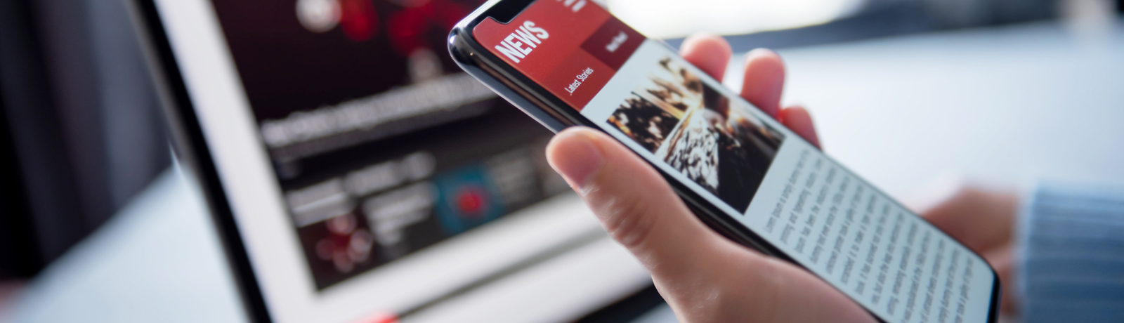 Image of a person look at news websites on a phone and laptop computer.