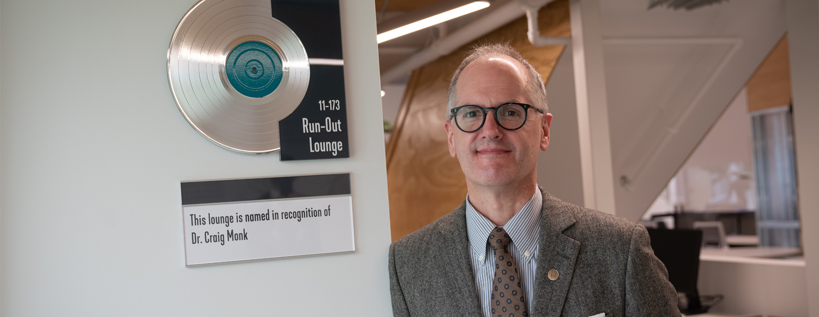 Dr. Craig Monk standing by signage for Run-Out Lounge