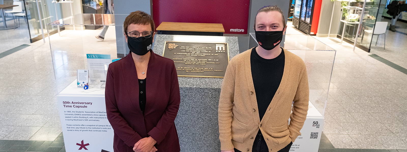 Dr. Annette Trimbee, president and vice-chancellor, and Myles Dykestra, SAMU president, unveil two new exhibits beside the original time capsule that highlight a selection of its contents.