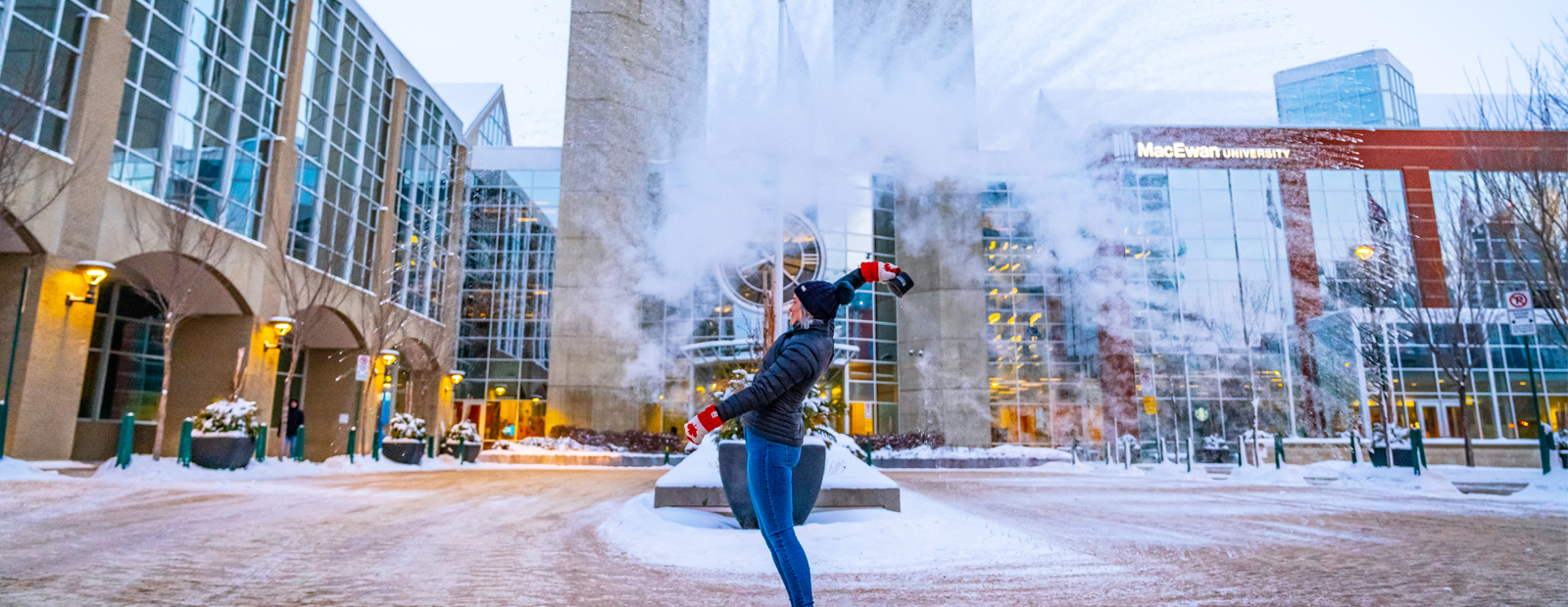 Student throwing snow in front of clock entrance on campus