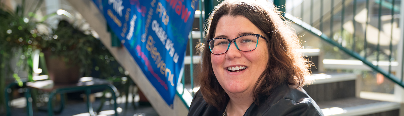 Image of Laura Gilmour smiling while sitting in the MacEwan University library.