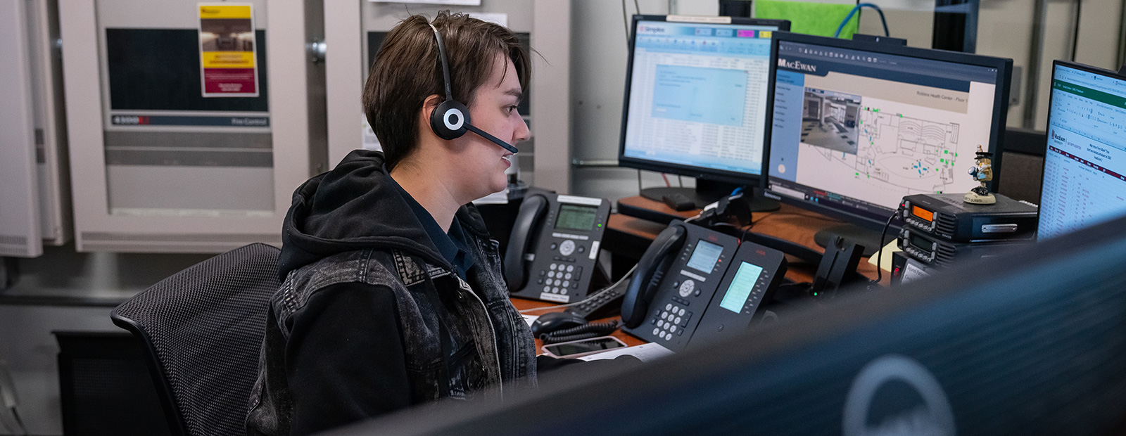 Emergency communications responder in front of a set of screens