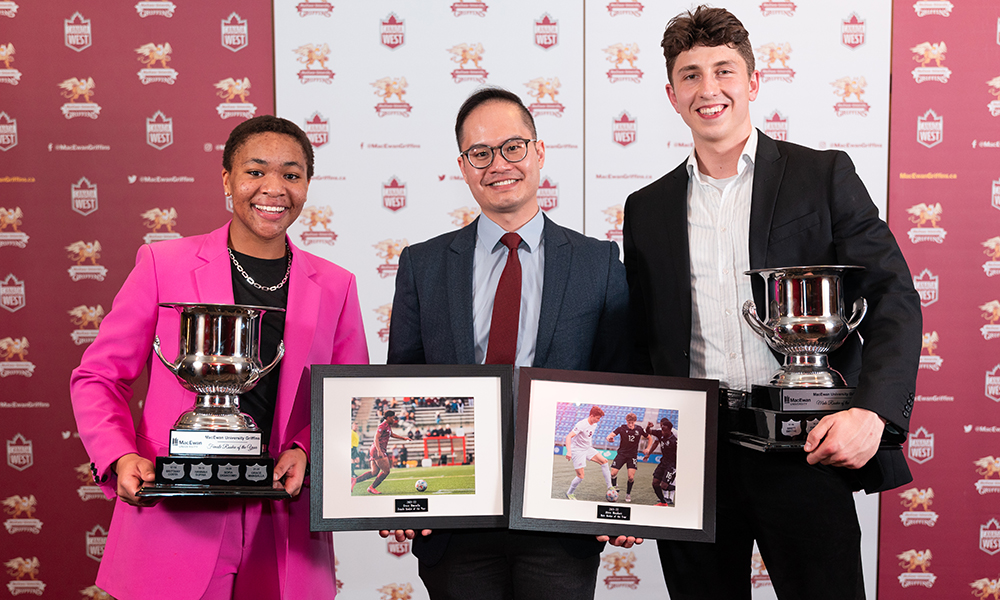 Athletes Grace Mwasalla and Alvin Mazaheri pose with trophies on either side of Tim Tang, who holds two certificates.