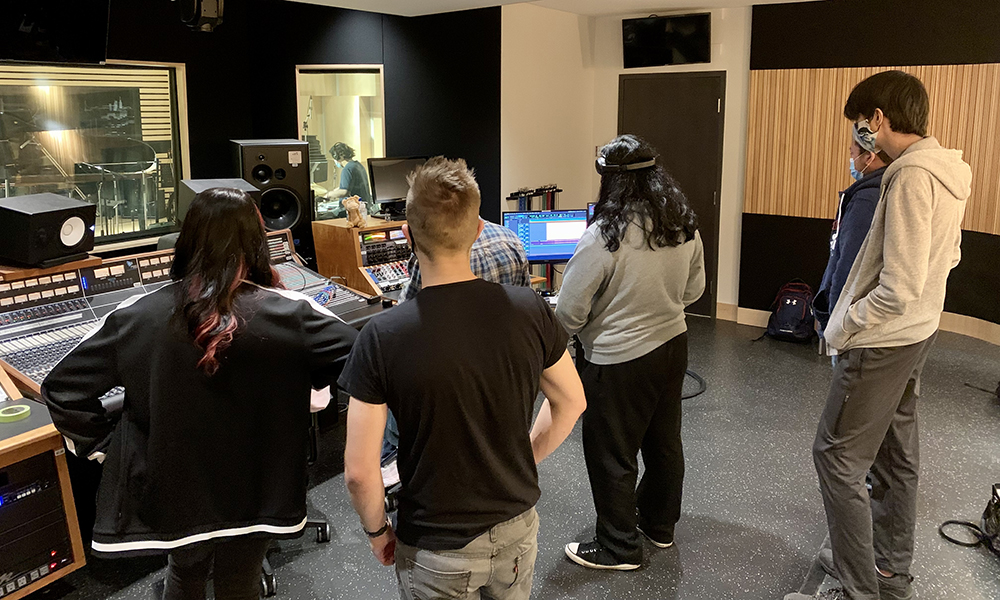 Students gather around a console in a recording studio