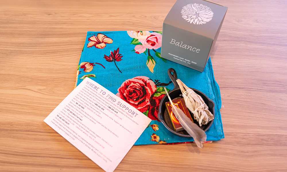 A box of tea and a sage burning kit are displayed on a blue floral scarf.