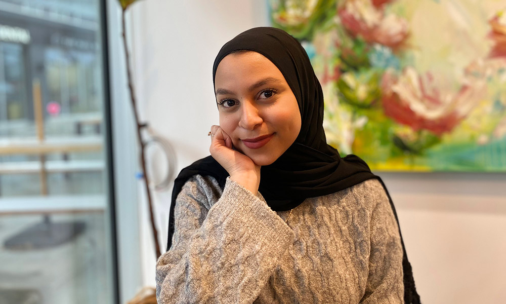 Fattima Deiab sits at a table in front of a floral painting