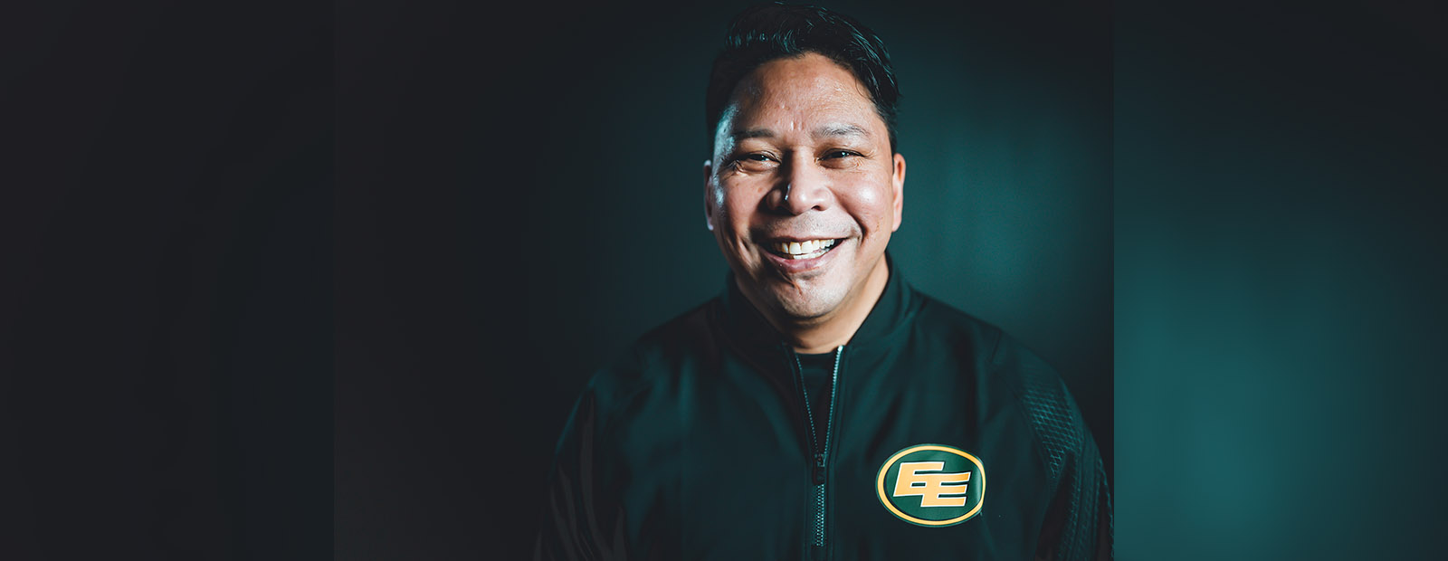 Victor Cui smiling and wearing an Edmonton Elks jacket