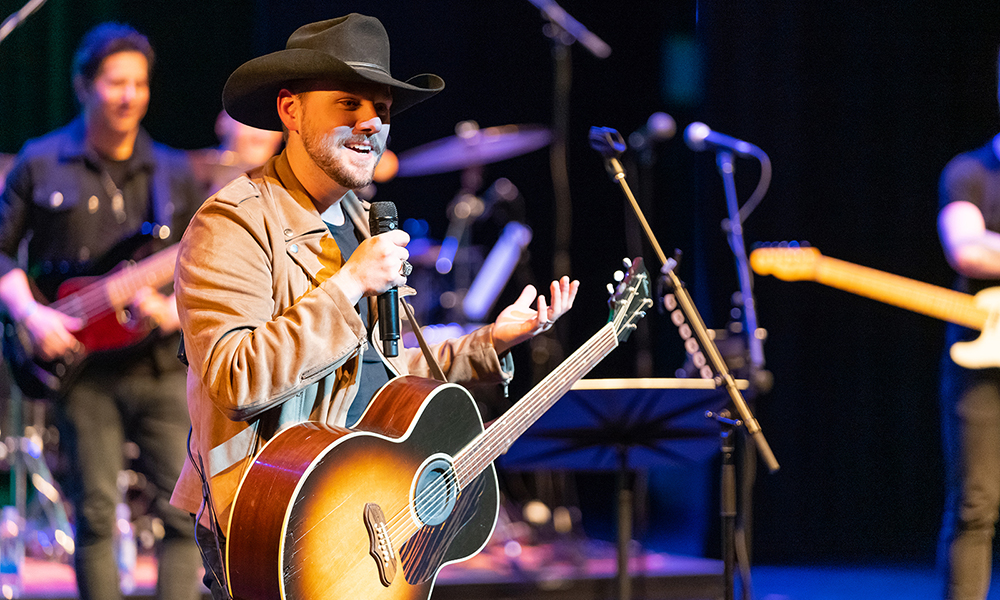 Image of country singer Brett Kissel, on stage, holding a guitar