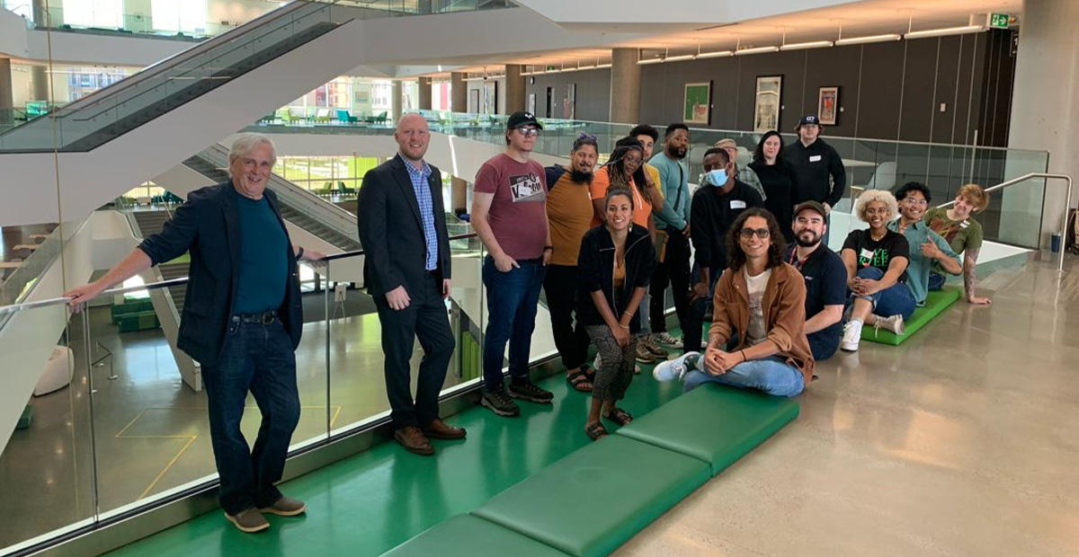 A group of student musicians stand with MacEwan staff and a TD representative in Allard Hall.