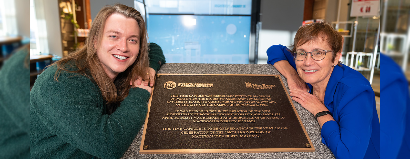 SAMU President Myles Dykes and MacEwan President and Vice-Provost Annette Trimbee lean against the granite pillar that houses the new time capsule