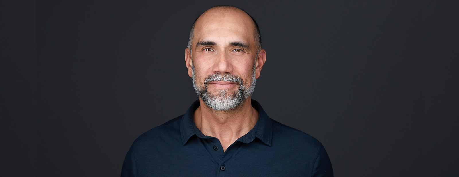 A headshot of Cameron Naqvi in front of a dark grey backdrop