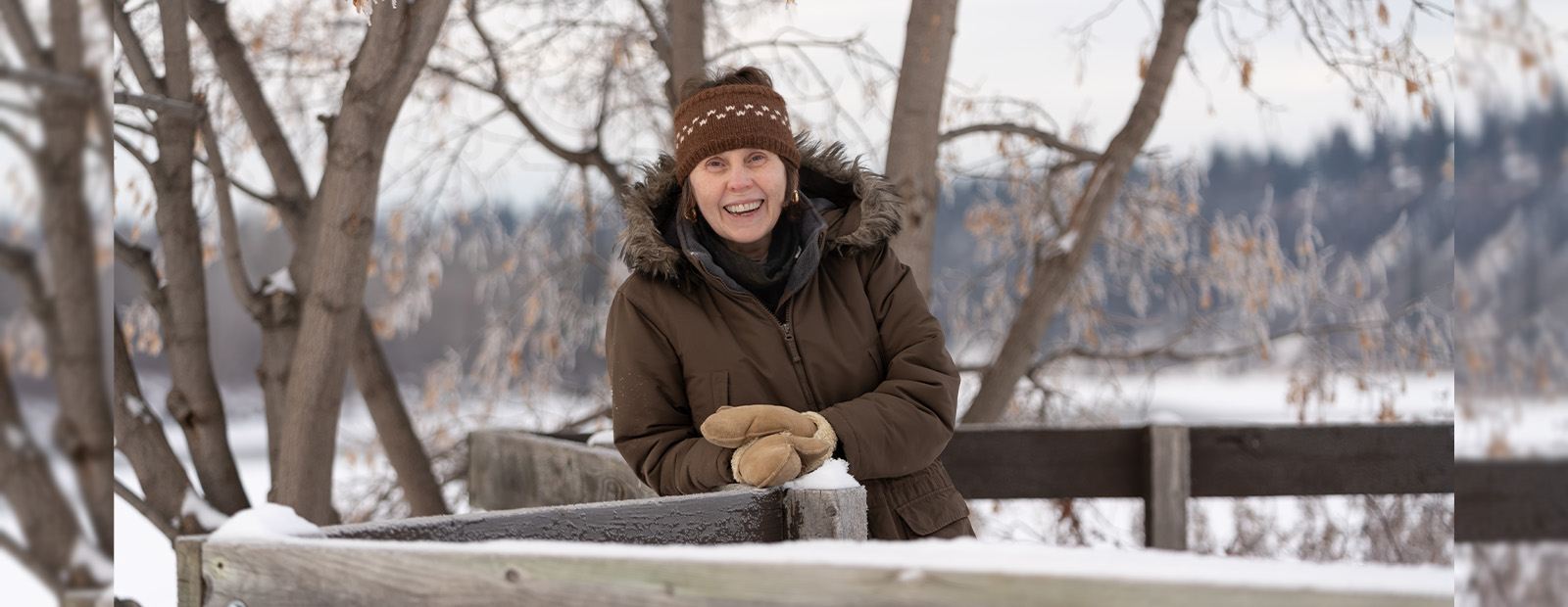 Audrey Whitson stands on a snowy bridge in Edmonton's river valley, smiling.