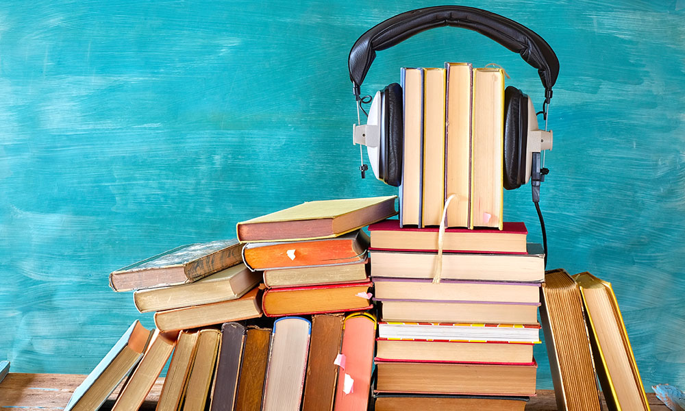 A pile of books held together with a pair of headphones