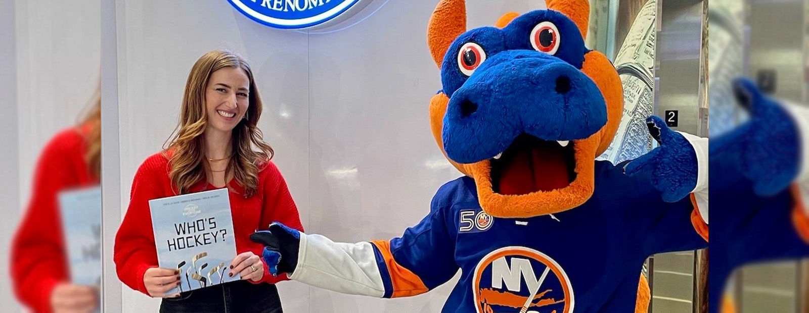 Nicola Pringle holds a copy of the children's book Who's Hockey? alongside the New York Islanders mascot Sparky the Dragon