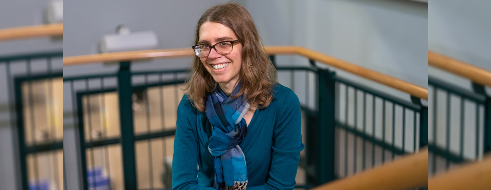 Vivian Binnema stands in a stairway in MacEwan and leans against the railing, smiling