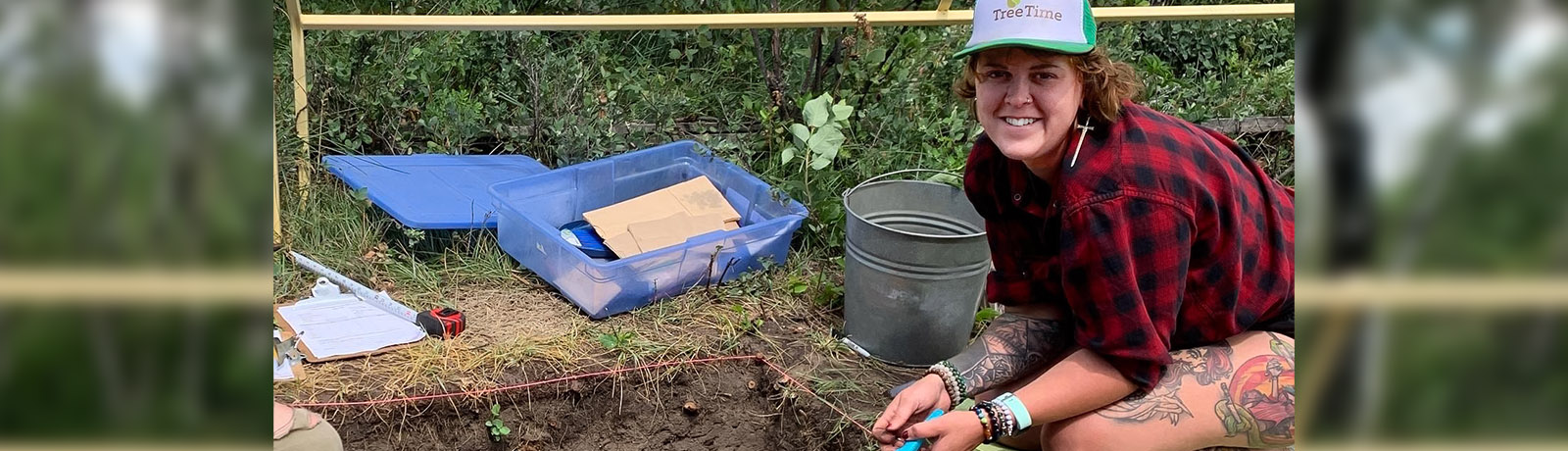 Ashley kneels alongside a dig site at Bodo