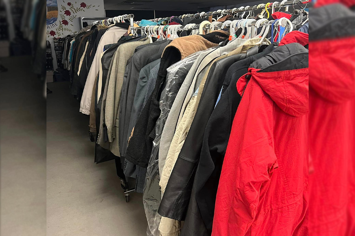 A rolling rack is stuffed with dozens of winter coats and jackets