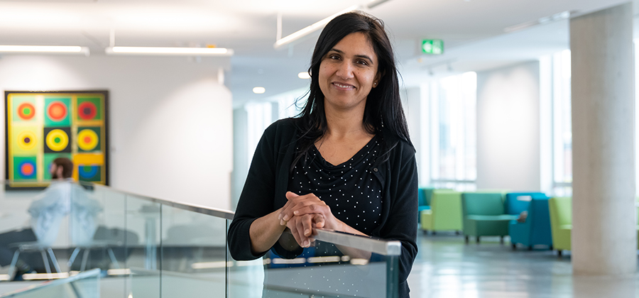 Neetu Sharma leans against a glass railing in Allard Hall