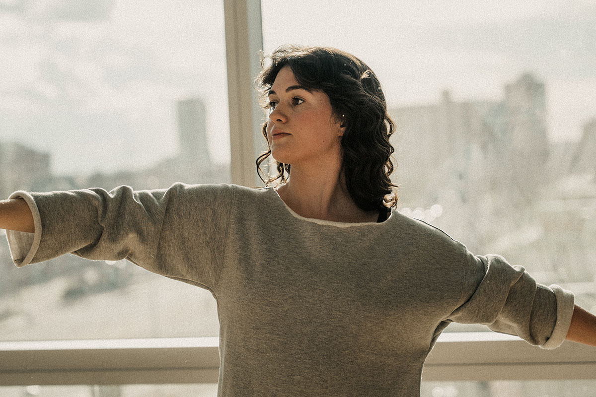 Lisa Kotelniski stands in front of a window holding a dance pose