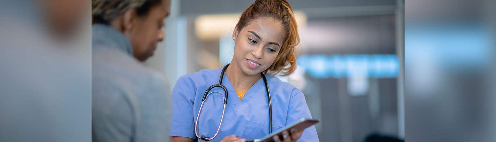 A nurse holds an ipad and speaks to a supervisor