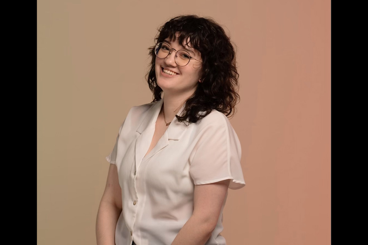 A woman in a white shirt and glasses smiles at the camera in a posed headshot