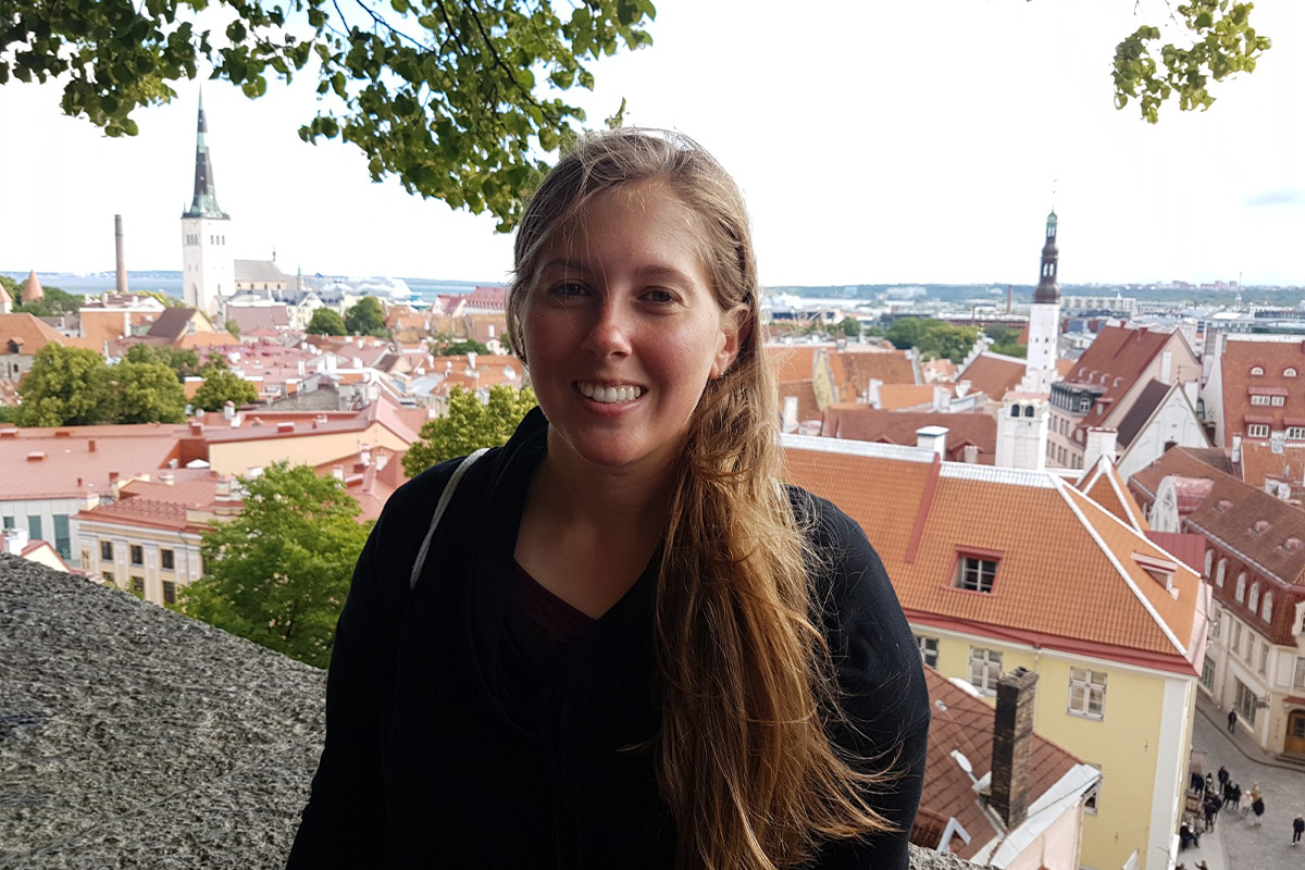 A woman stands on a balcony overlooking a city below