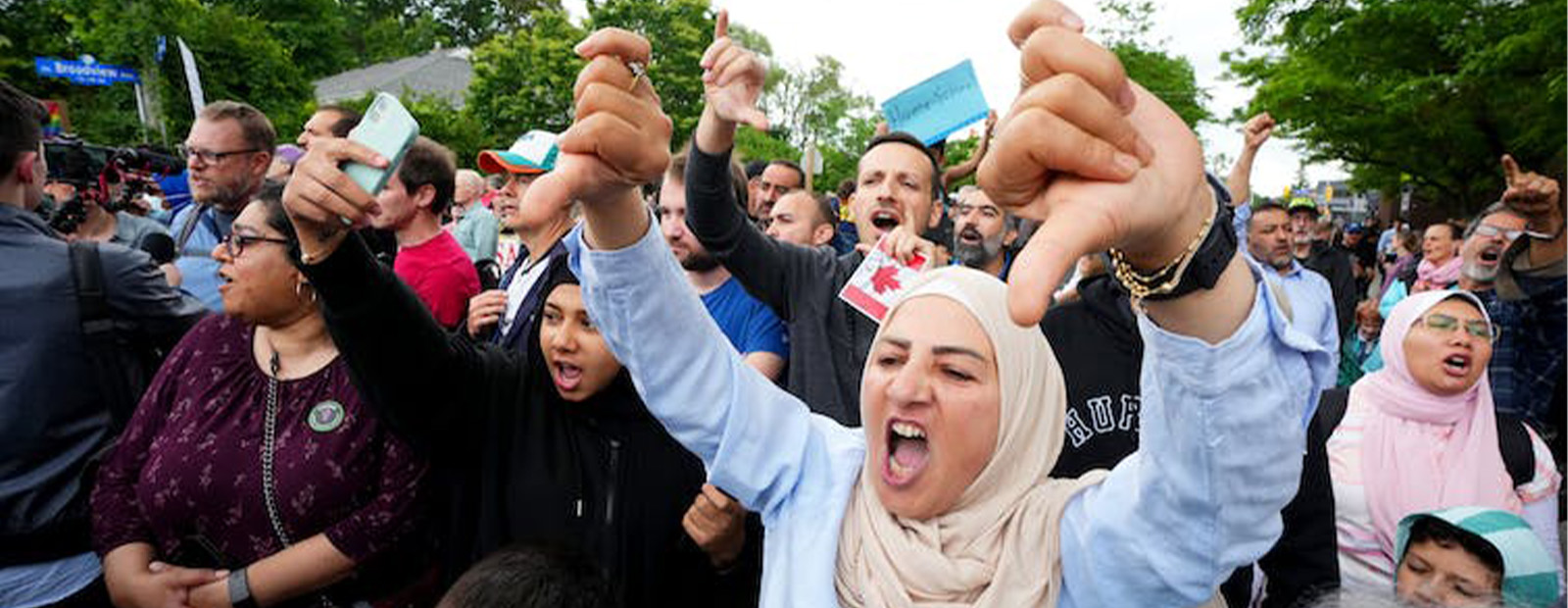 A protester in a crowd makes a thumbs-down gesture